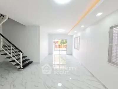 Spacious modern living room with marble flooring and staircase, perfect for family gatherings.