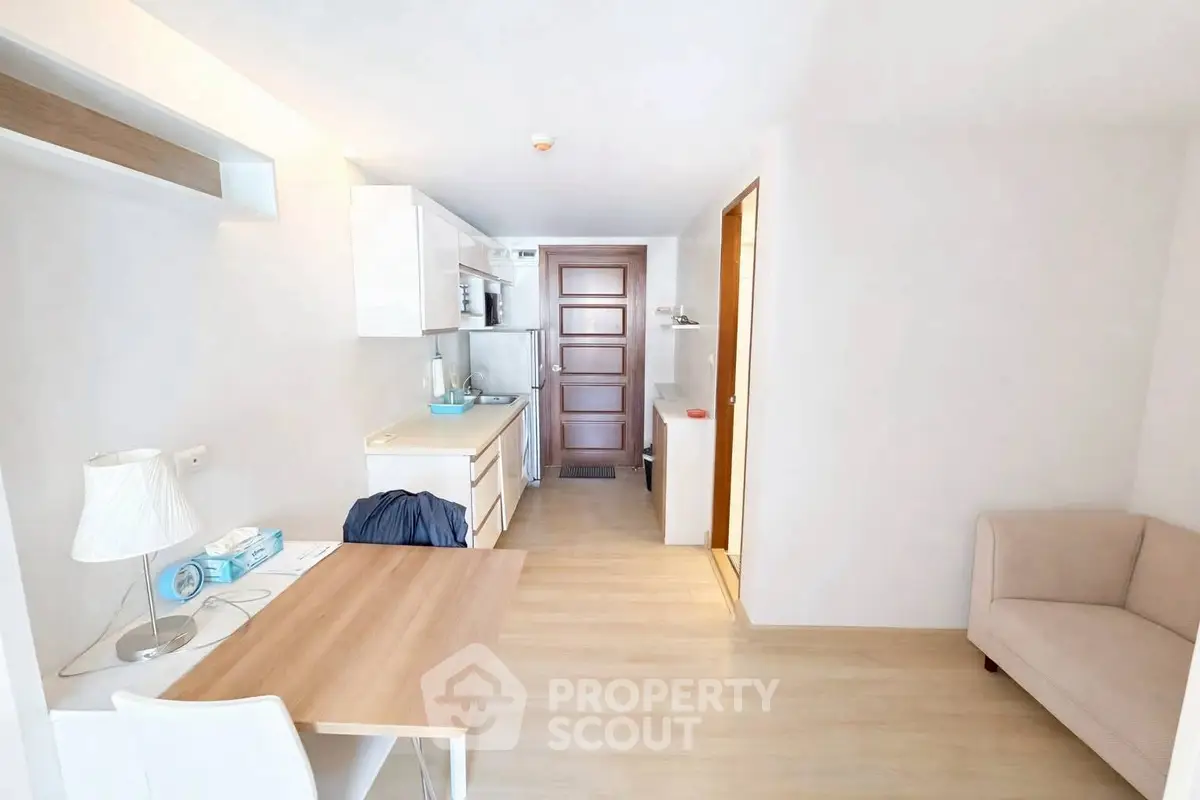 Modern minimalist apartment interior with compact kitchen and cozy seating area.