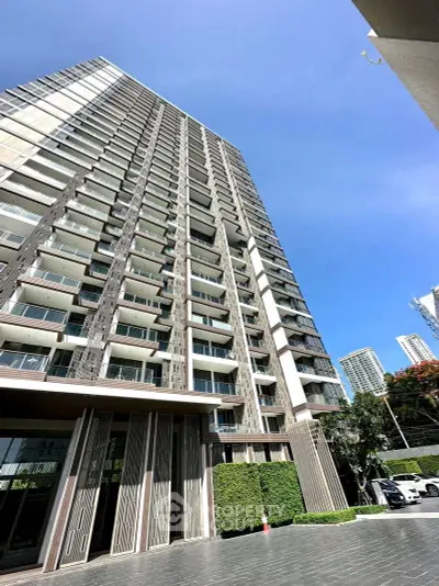 Stunning modern high-rise building with sleek design and spacious balconies in urban setting.