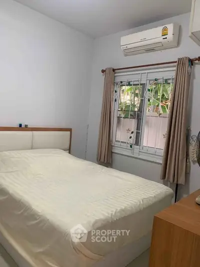 Cozy bedroom with air conditioning and window view, perfect for relaxation.
