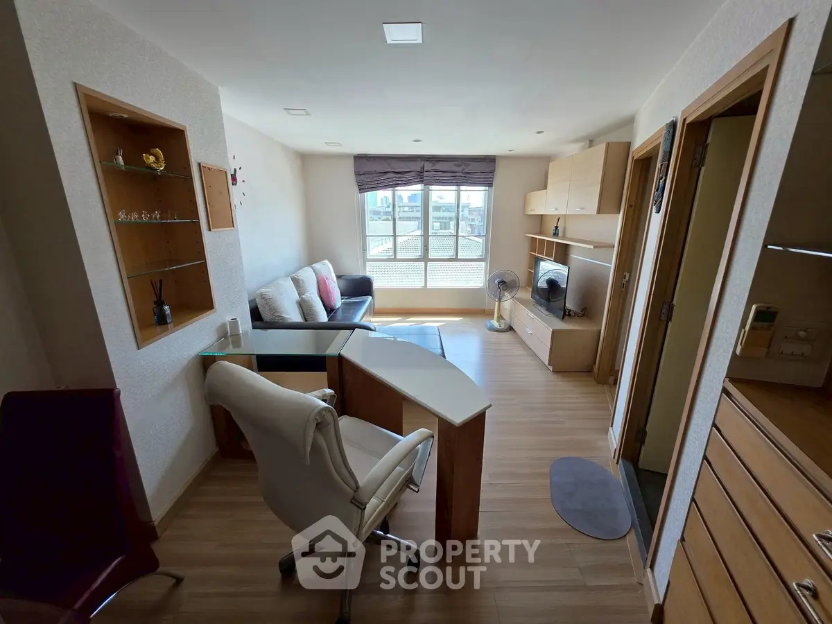 Modern living room with sleek furniture and large window offering city view.