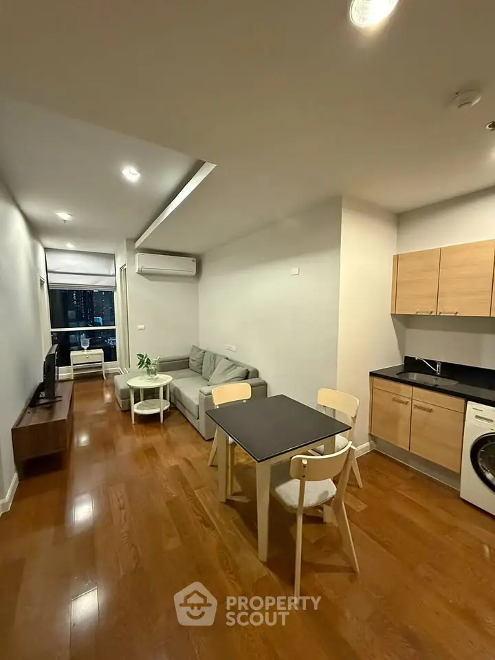 Modern open-plan living room with kitchen, featuring wooden floors and contemporary furniture.