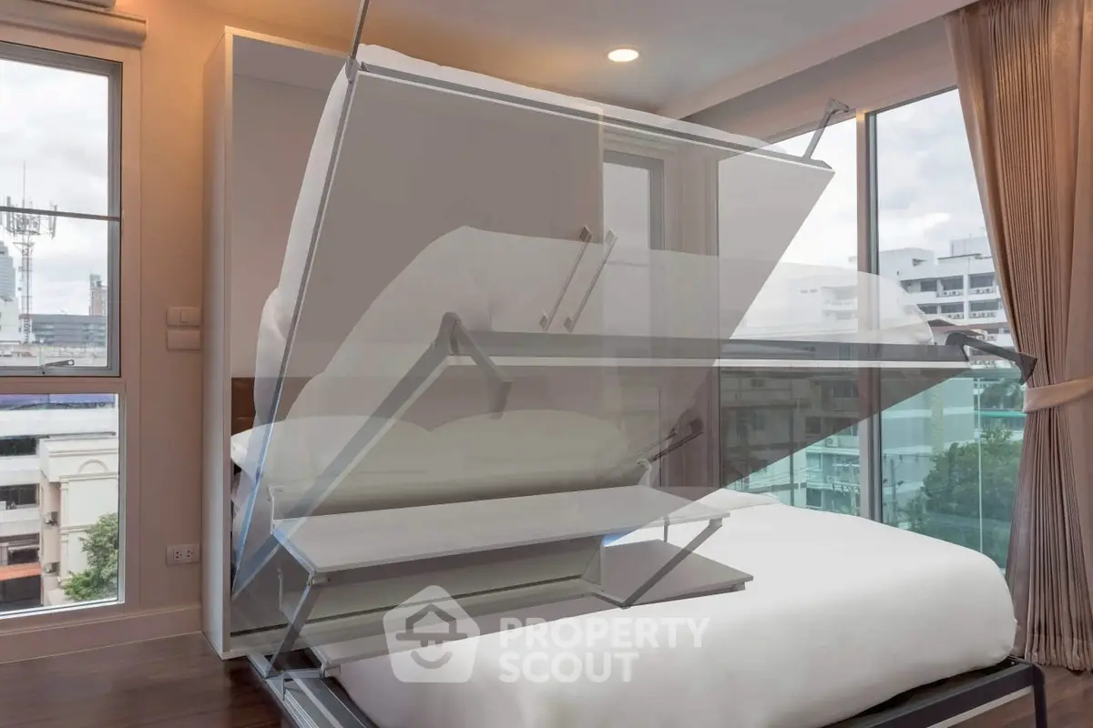 Modern bedroom with innovative foldable bed design and large windows offering city views.