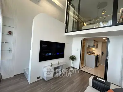 Modern duplex living room with high ceiling and mezzanine, featuring sleek design and open kitchen layout.