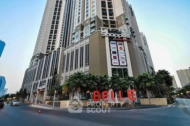 Modern high-rise building with retail shops and palm-lined entrance in urban setting.