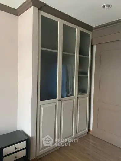 Elegant built-in wardrobe with frosted glass doors in a modern bedroom setting.