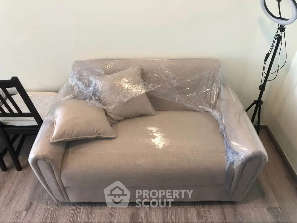 Cozy small living room with a wrapped beige sofa and modern decor