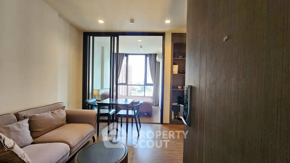 Modern living room with cozy sofa and dining area, featuring large windows with city view.