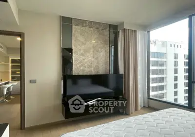 Modern bedroom with large windows and city view, featuring sleek TV setup and elegant decor.