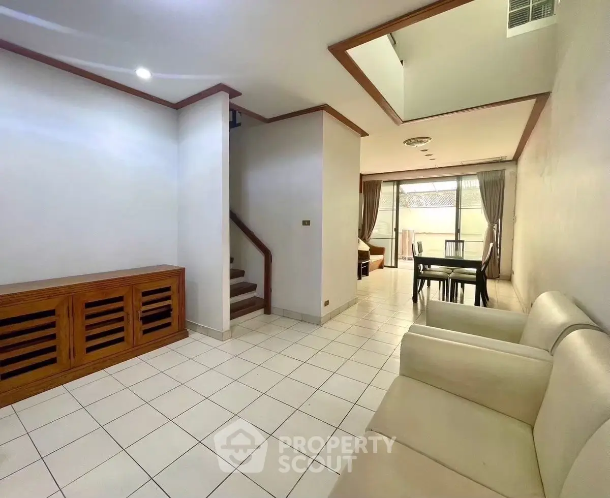 Spacious living room with dining area and staircase, featuring modern design and ample natural light.