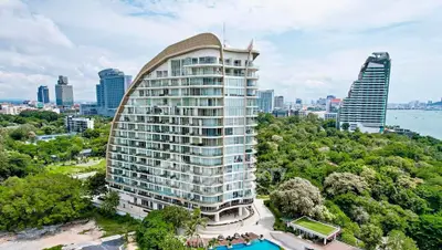 Stunning modern high-rise building with lush greenery and ocean view, perfect for luxury living.