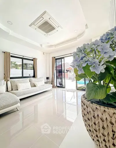 Spacious living room with elegant decor and pool view, featuring plush seating and natural light.