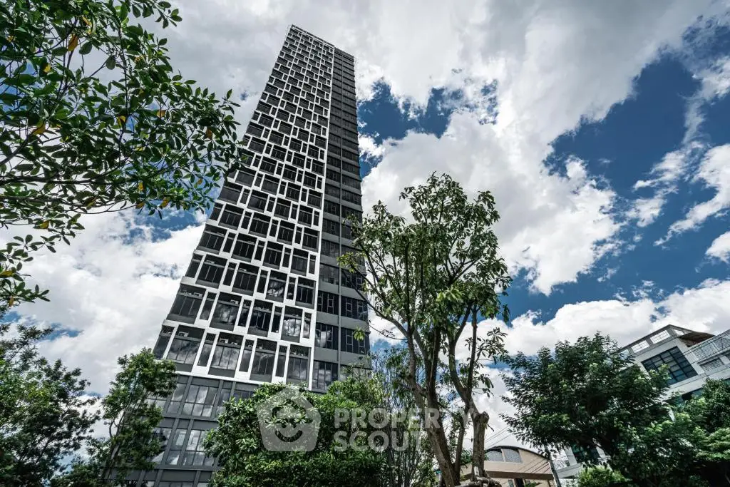 Stunning modern high-rise building with lush greenery and blue sky backdrop.
