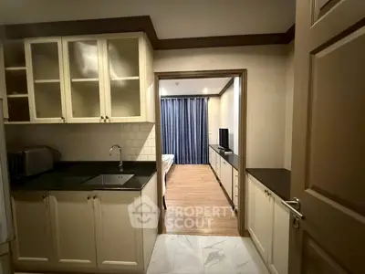 Charming kitchen with open layout leading to cozy bedroom, featuring elegant cabinetry and modern appliances.