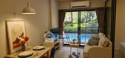Charming living room with pool view, cozy seating, and elegant dining setup in modern apartment.