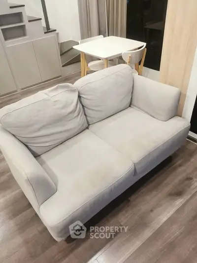 Cozy modern living room with stylish gray sofa and wooden flooring, perfect for relaxation.