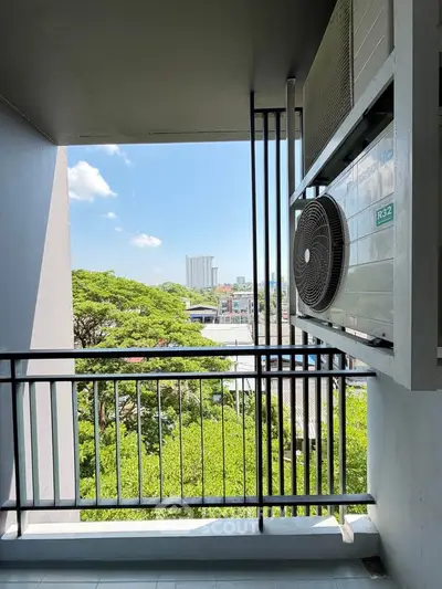 Charming balcony with lush green view and air conditioning unit, perfect for relaxation.