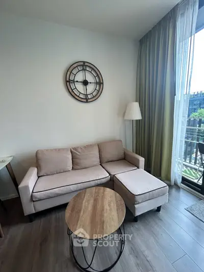 Cozy living room with modern sofa and stylish decor, featuring a large window with green curtains and a view of the balcony.
