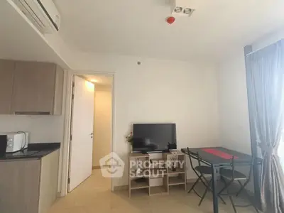 Modern apartment interior with compact kitchen and cozy dining area, featuring a TV and air conditioning.