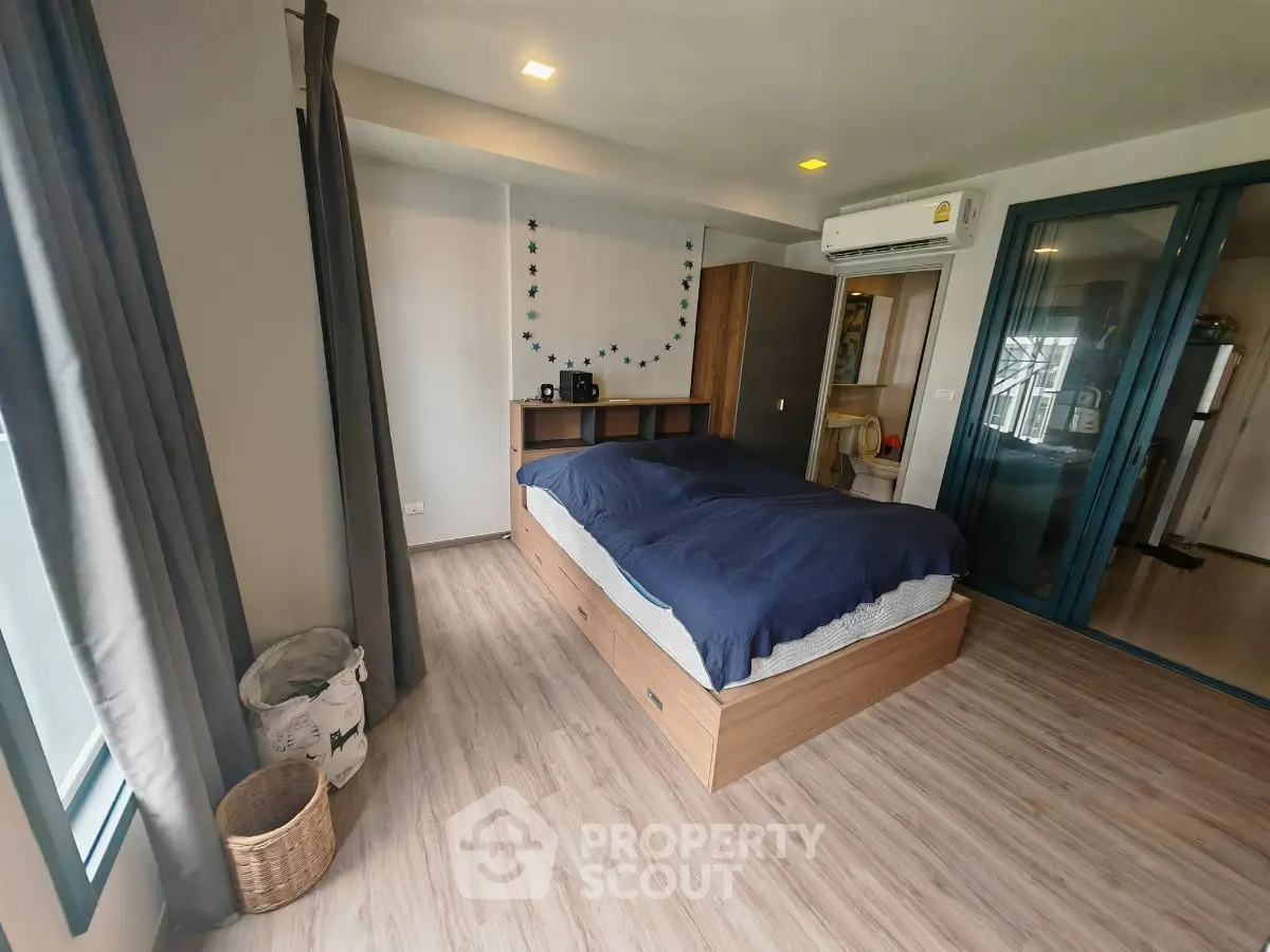 Spacious bedroom with modern decor and large windows in a stylish apartment.