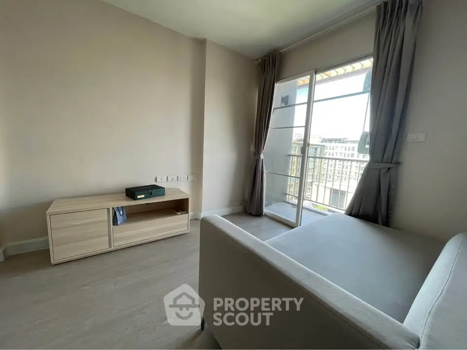 Spacious living room with balcony access and modern furnishings in a high-rise apartment.