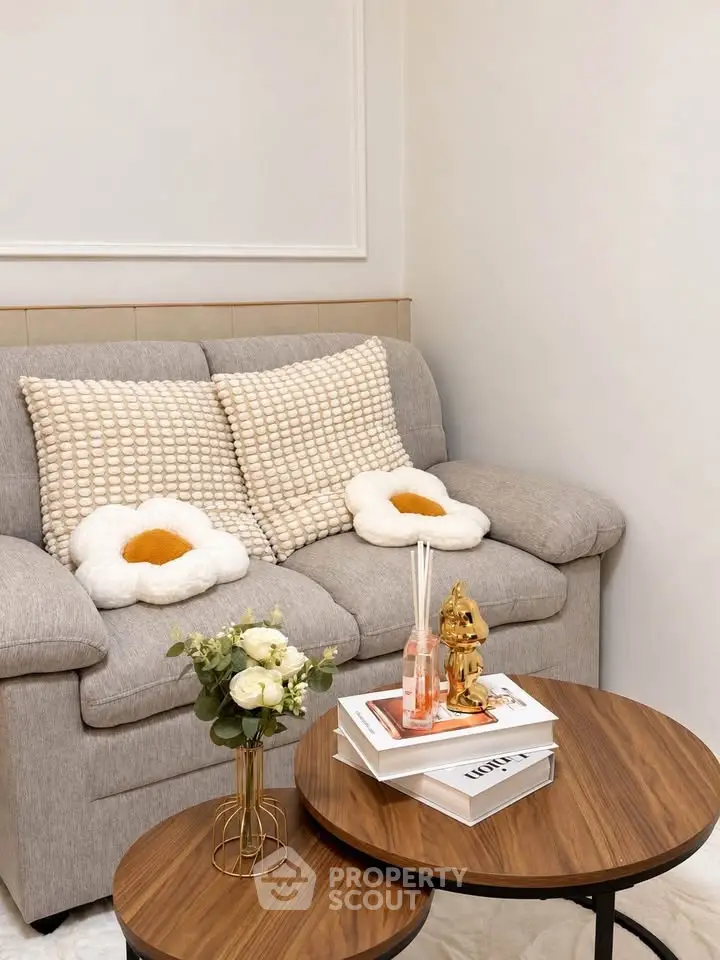 Cozy living room with stylish sofa and decorative pillows, featuring elegant coffee tables and floral accents.