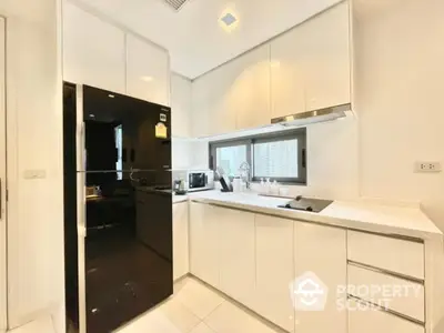 Modern kitchen with sleek white cabinets and black appliances in a luxury apartment