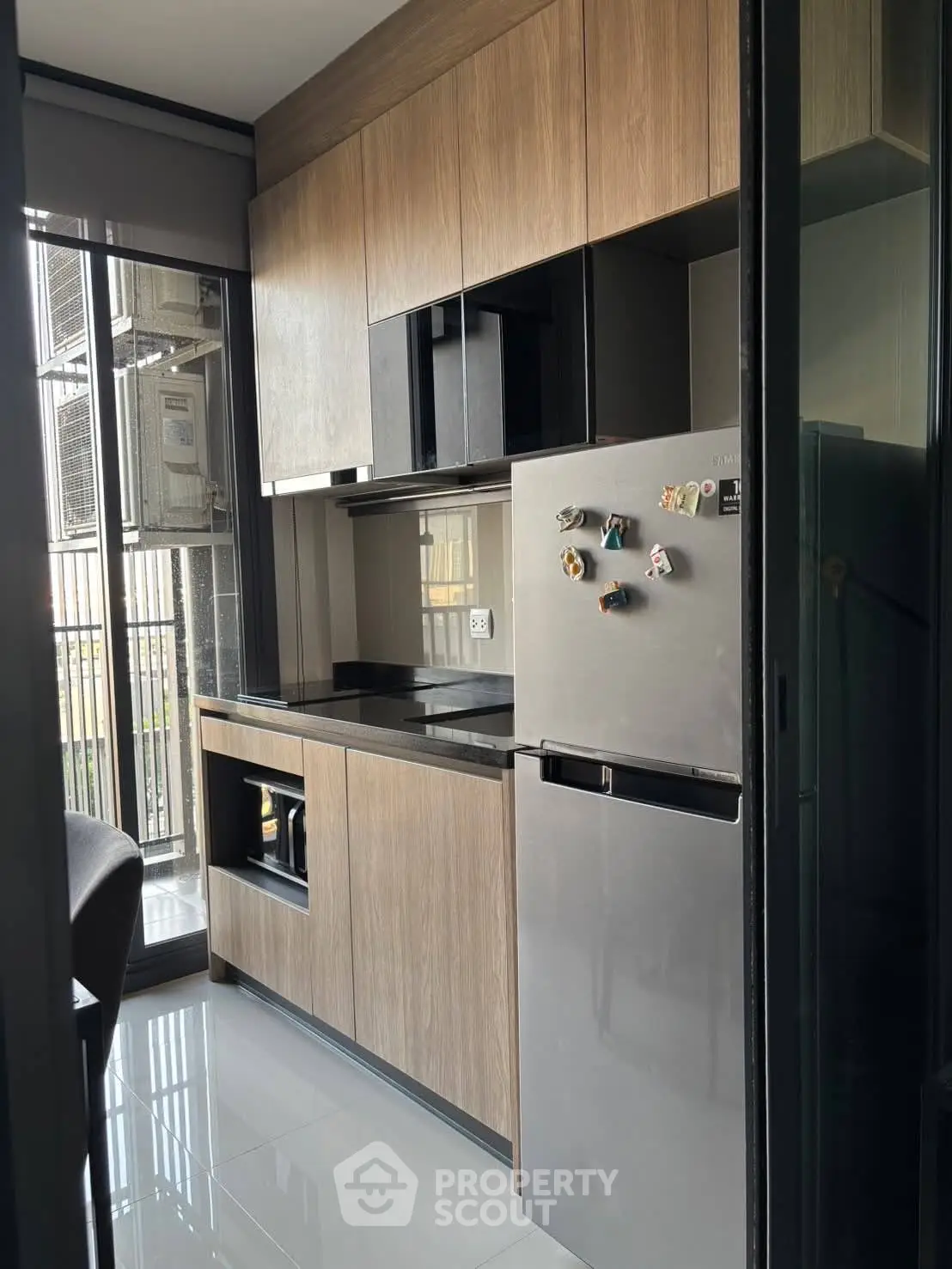 Modern kitchen with sleek cabinetry and stainless steel fridge in a compact apartment setting.