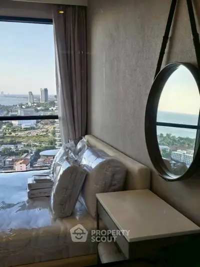 Luxurious bedroom with stunning city and sea view, modern decor and large window.