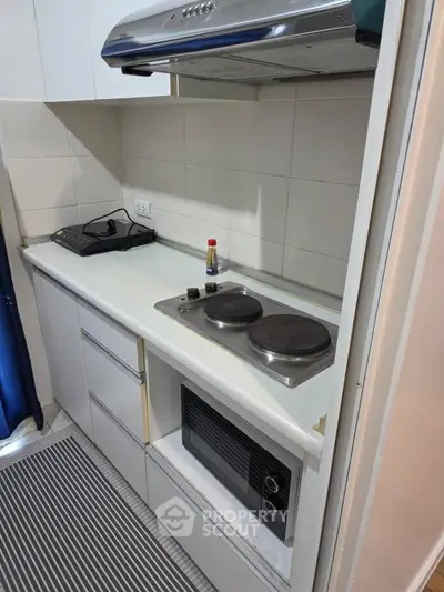 Compact kitchen with electric stove and microwave in modern apartment