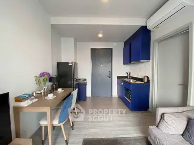 Modern apartment interior with stylish kitchen and cozy living area, featuring sleek blue cabinets and elegant decor.