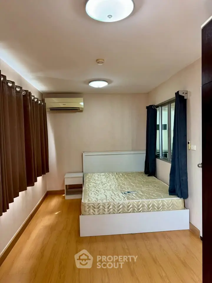 Spacious bedroom with natural light, featuring a comfortable bed and modern air conditioning.