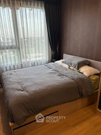 Cozy bedroom with large window and modern decor, perfect for relaxation and comfort.