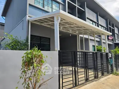 Modern townhouse exterior with gated driveway and covered parking area.