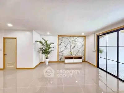 Spacious modern living room with elegant marble accent wall and large windows.