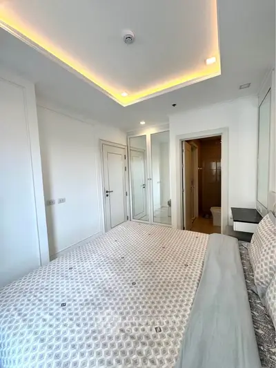 Modern bedroom with stylish ceiling lights and ensuite bathroom in luxury apartment.