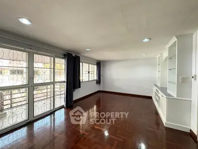 Spacious living room with hardwood floors and large windows for natural light.