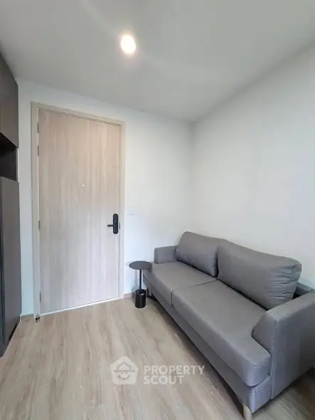 Modern living room with sleek gray sofa and wooden flooring, perfect for cozy relaxation.