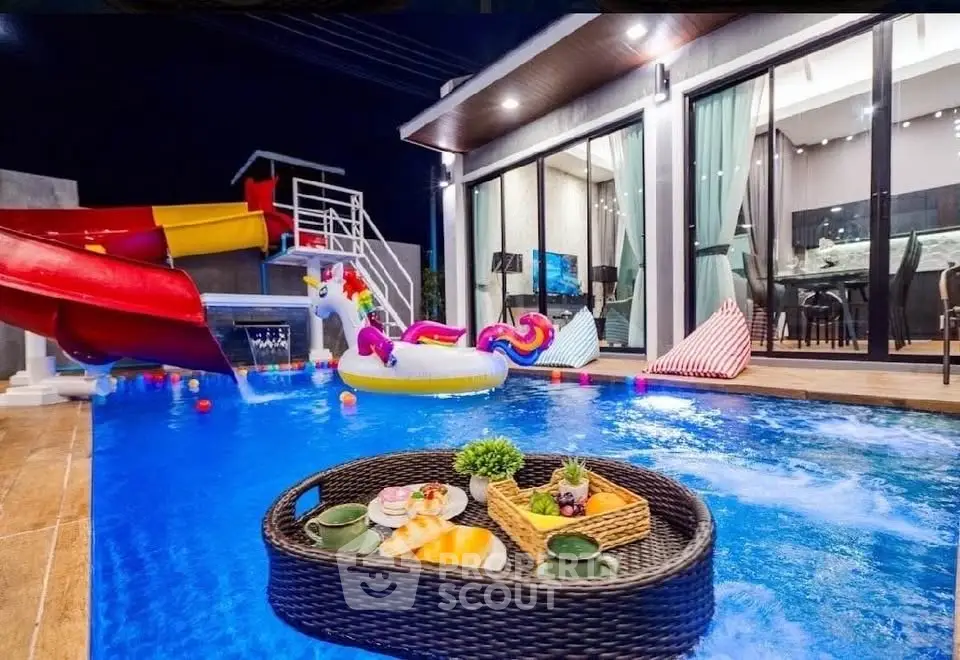 Luxurious poolside view with modern home and vibrant slide, perfect for entertaining and relaxation.