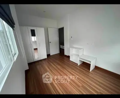 Spacious bedroom with wooden flooring and modern white furniture