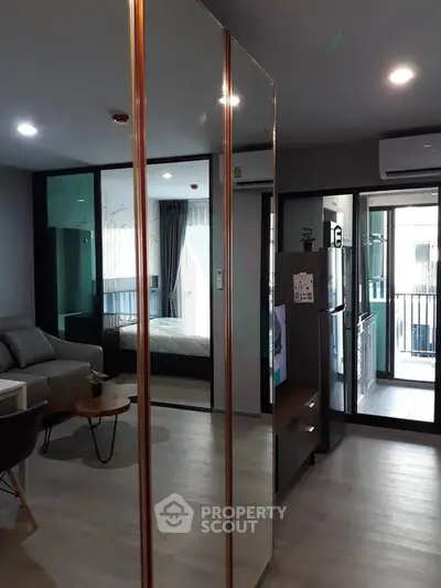 Modern apartment interior with open layout, featuring living room, bedroom, and kitchen with balcony access.