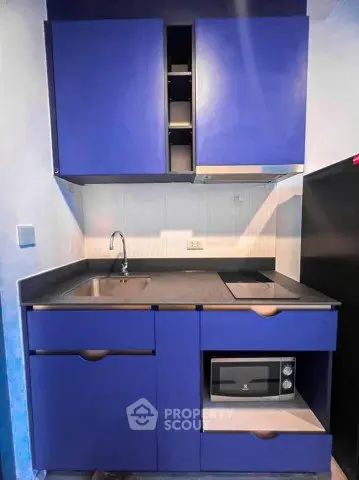 Modern compact kitchen with blue cabinets and built-in microwave
