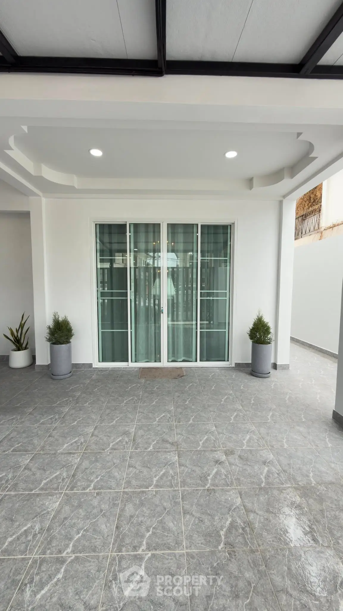 Modern covered entrance with sliding glass doors and elegant tile flooring.