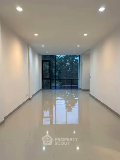 Spacious modern living room with large windows and glossy tiled floors
