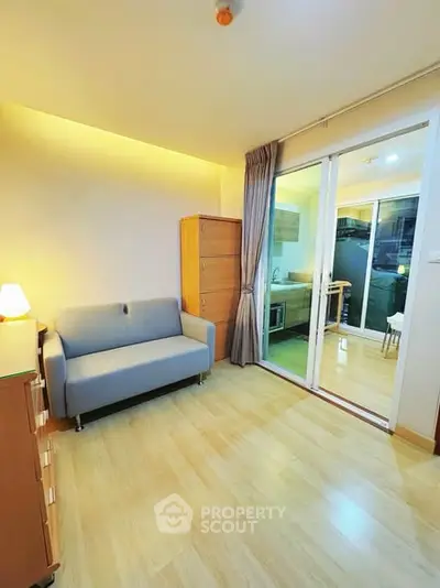 Cozy living room with modern decor and sliding glass doors leading to a compact kitchen area.
