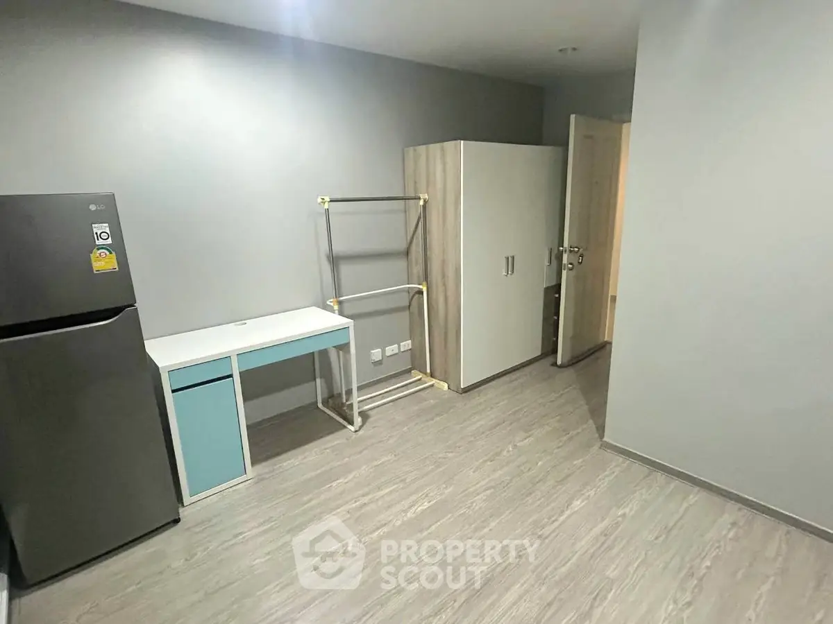 Modern apartment interior with fridge, desk, and wardrobe in minimalist design.