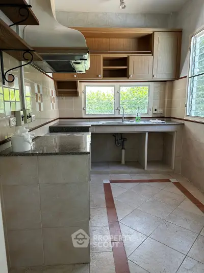 Spacious kitchen with ample storage and natural light, featuring tiled flooring and modern fixtures.