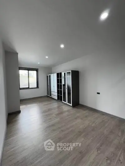 Spacious empty room with large window and modern wardrobe, perfect for customization.