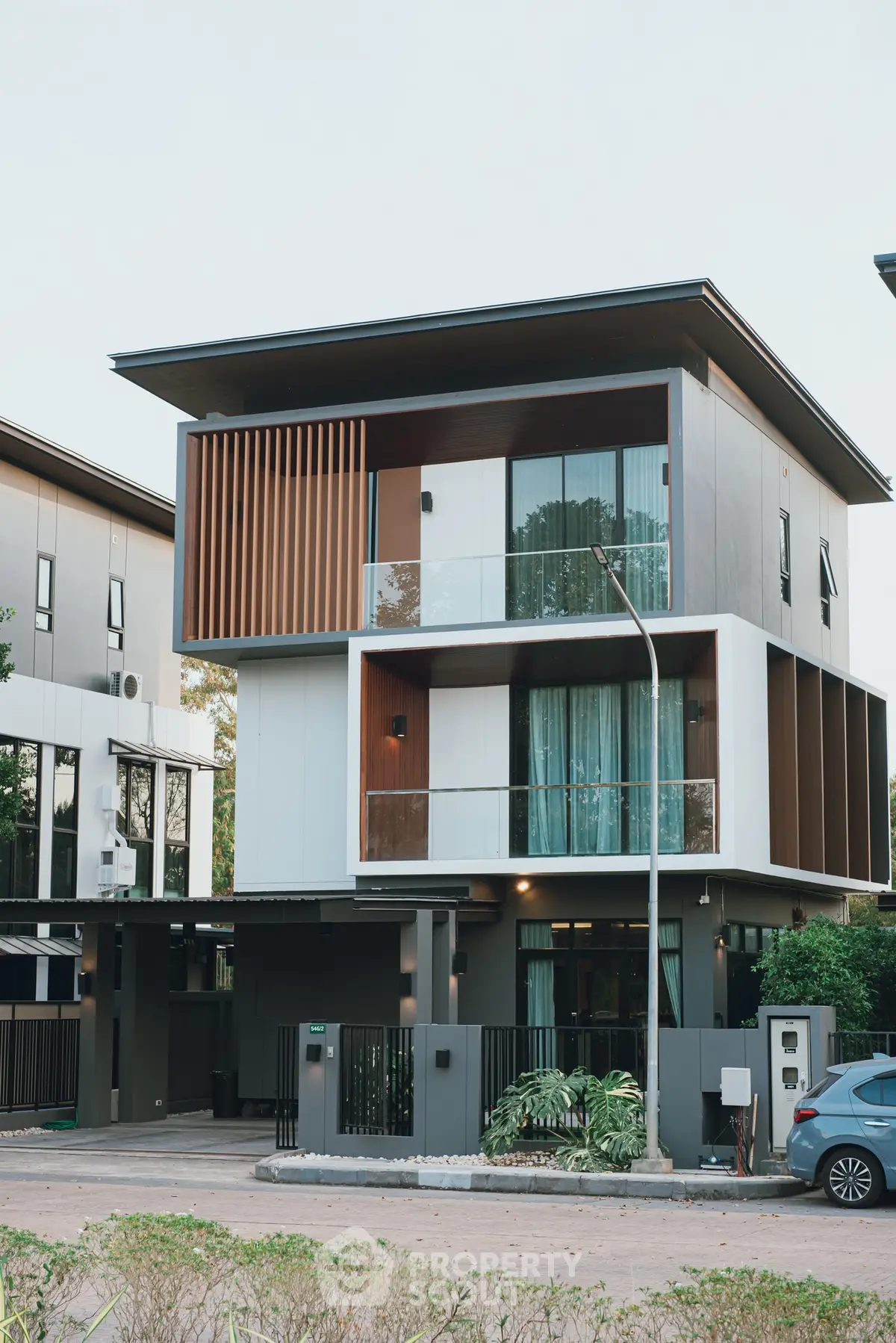 Modern three-story house with sleek design and large windows in a suburban neighborhood.