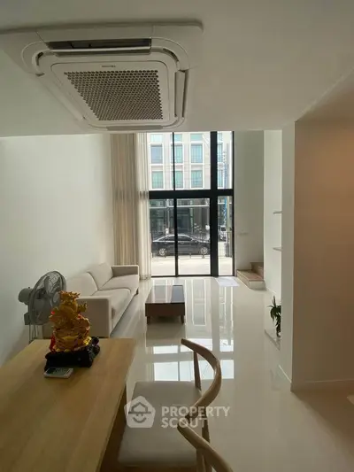 Modern living room with high ceilings and large windows, featuring minimalist furniture and a sleek design.